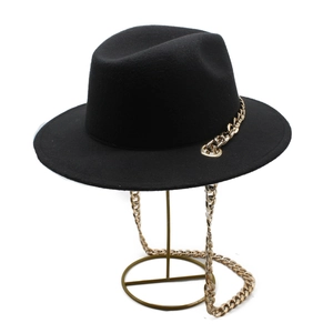 Classic black fedora hat with bold gold metal chain accent on a minimalist stand