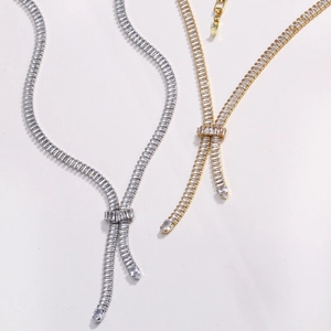 Dettaglio di collane a V oro e argento con fiocco in zirconi e nappe con frange