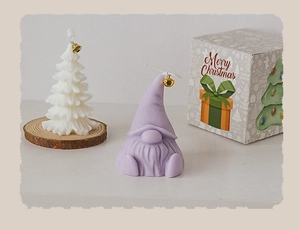 Detail of Christmas tree and gnome scented candles with gold bells and gift box