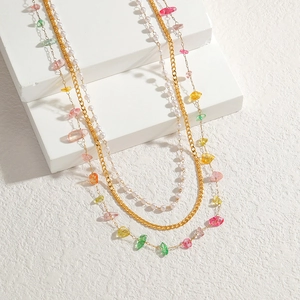 Chic layered necklace with gold chains, pearls, and colorful natural stones on stone blocks