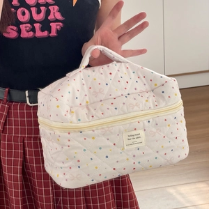 Quilted makeup bag with pink polka dots and bow print featuring a top handle