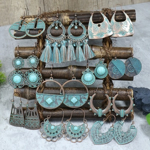 Close-up of bohemian earrings set featuring turquoise beads and bronze tassels on display