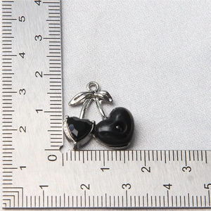 Detailed macro view of silver cherry charm with black heart stones on measuring ruler