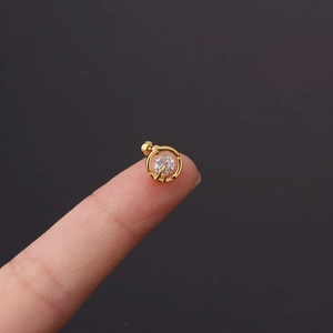 Macro detail of a 20g gold zircon tragus earring with a secure screw ball back on fingertip