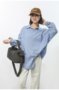 Detail showing grey quilted nylon shoulder bag with knotted strap and striped shirt