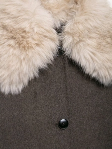 Detail of faux fur collar in light khaki and dark brown wool coat with black buttons