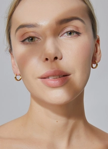 Close-up of minimalist gold plated round hoop earrings worn on a model's ear