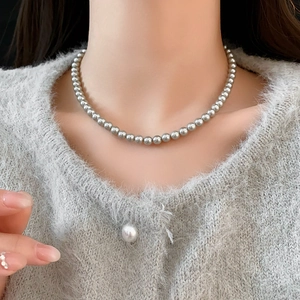 Close-up of minimalist gray pearl choker necklace worn with a gray knit cardigan