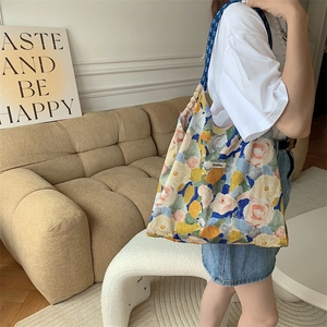 Detailed close-up of a floral oil painting canvas tote bag with shoulder straps and label