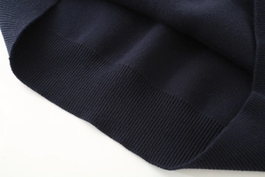 Detailed view of the ribbed cuff and knit texture on the navy blue polo sweater
