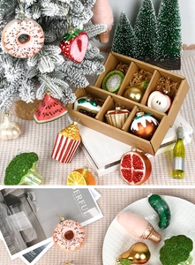 Macro shot of assorted glass fruit and vegetable Christmas tree ornaments in decorative settings