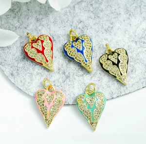 Macro detail of five colorful 18K gold-plated heart pendants with zircon and enamel wing patterns