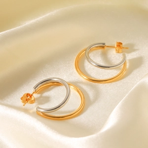 Modern two-tone gold and silver stainless steel double hoop earrings on silk background