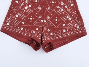 Detail der roten Shorts mit aufwendiger weißer geometrischer Stickerei und Nähten