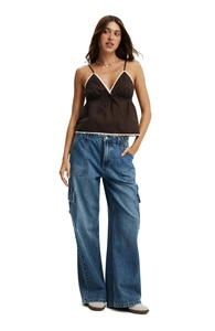 Full view of women's blue multi-pocket cargo jeans paired with a brown camisole top