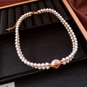 Detail of vintage gold plated double layer pearl necklace with orange gemstone pendant