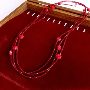 Long multi-layer beaded necklace with red glass flowers and faceted beads on velvet