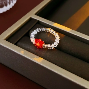 Macro shot of handmade beaded flower ring featuring red petals and transparent beads