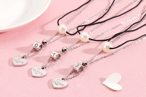 Detail of silver heart pendants engraved with Love and numeric beads on three-piece necklaces