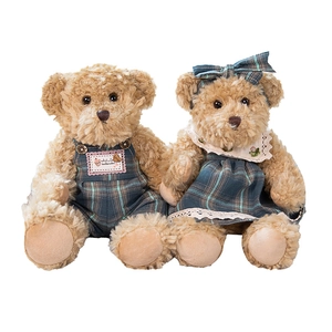 Pair of plush teddy bears in green and blue plaid outfits on a white background