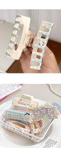 Close-up of a blue and white plaid acrylic hair claw clip with metal spring details
