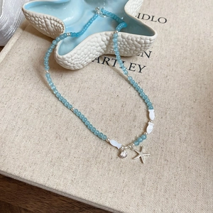 Détail du collier de perles bleu clair avec pendentifs étoile de mer et coquillage