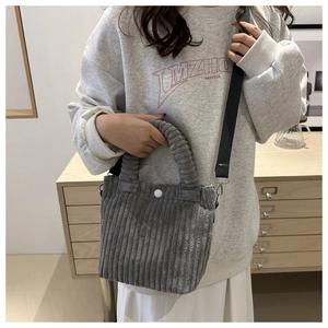 Detail of grey corduroy crossbody bag featuring a soft texture and white button closure
