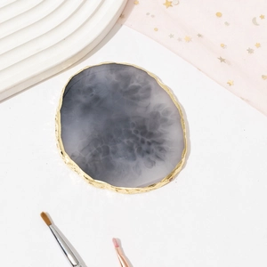 Top view of dark grey resin agate nail palette with gold rim and natural cloud texture