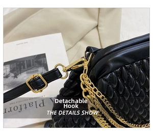 Detail of gold metal hook and detachable chain strap on black pleated quilted leather bag