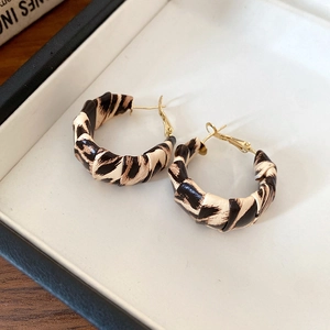 Detail of leopard print C-hoop earrings with gold hardware in a gift box