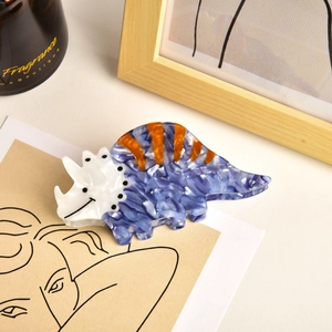 Detail of blue triceratops hair claw clip made of acetate with orange stripe accents