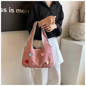 Détail du sac seau rose avec cœurs 3D colorés porté par un mannequin en noir