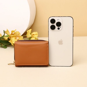Brown leather mini wallet shown next to a smartphone to demonstrate compact size