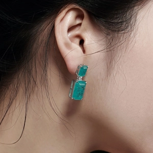 Macro shot of double-layered emerald green earrings in 925 sterling silver worn by model