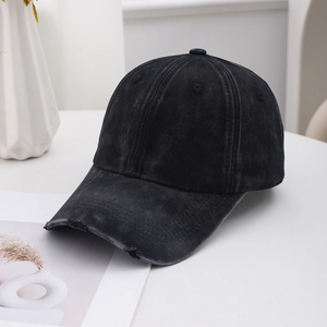 Detail view of washed black denim baseball cap with distressed brim on modern desk