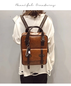 Detail view of vintage brown leather backpack with metal buckles and panda charm
