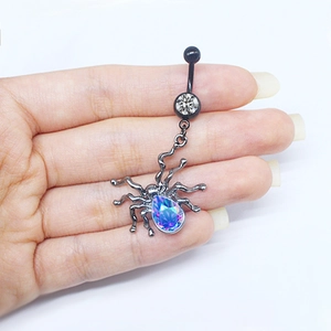 Detailed close-up of a spider navel piercing with blue gradient crystals held in hand
