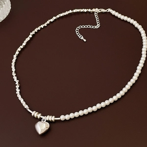 Detail view of heart pendant necklace with split pearl and irregular silver beads