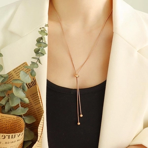 Macro detail of rose gold Y-shaped necklace with metal beads on a modern snake chain