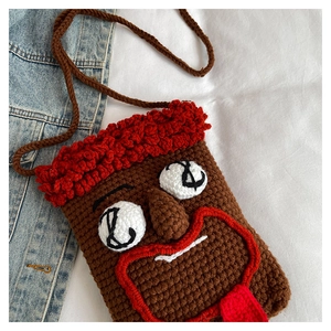 Detail der lustigen handgehäkelten Tasche mit Gesichtsdesign auf Jeanshintergrund
