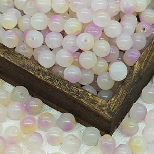 Detailed view of 10mm gradient purple glass beads scattered around a vintage wooden box