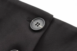 Gros plan du tissu sergé fin et d'un bouton sur un costume noir pour femmes