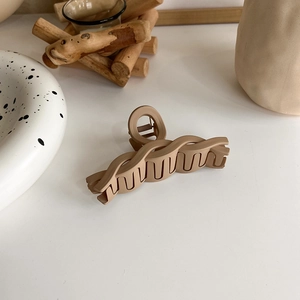 Detail of matte coffee brown wavy hair claw clip showing a textured resin finish