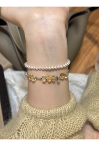 Detail of layered bracelet set with white pearls and yellow citrine beads on wrist