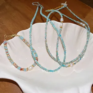 Minimalist pearl and light blue beaded jewelry set on white decorative shell tray