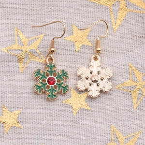 Detailed macro view of snowflake earrings with green enamel and red rhinestones on linen