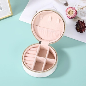 Top view of a round white velvet jewelry box featuring pink lining and storage sections
