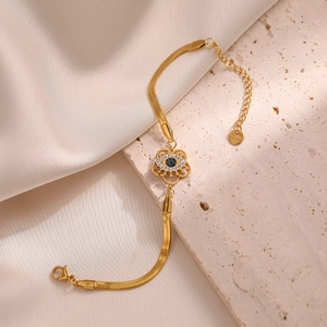 Elegant gold evil eye snake chain bracelet with blue zircon inlay on a stone background