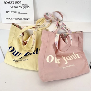 Detail of floral lining and printed quote on a minimalist canvas tote bag in soft colors