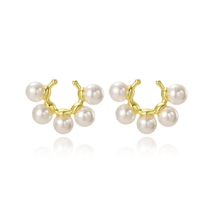 Dettaglio di eleganti ear cuff dorati con cinque perle bianche disposte a ventaglio